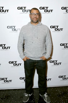 Jordan Peele in a grey sweater and black pants at the 'Get Out' movie premiere