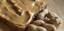 Peanut butter on bread and peanuts next to it