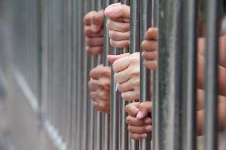 People at the Washington state prison holding onto the bars of their cells and sticking their hands ...