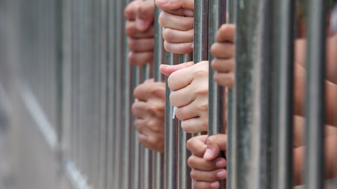 People at the Washington state prison holding onto the bars of their cells and sticking their hands ...