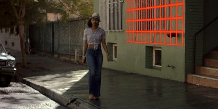 Woman in a crop top, blue jeans and white hat walking down the street