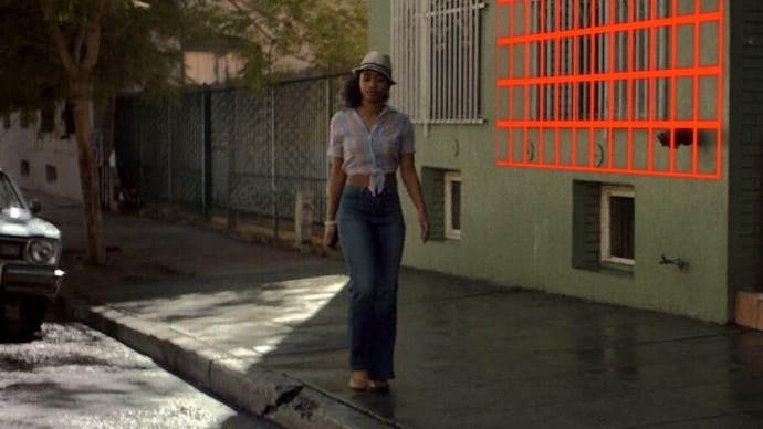 Woman in a crop top, blue jeans and white hat walking down the street