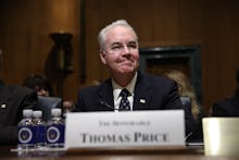 Thomas Price sitting behind a white cardboard sign that says his name on it 