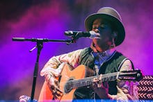 Lauryn Hill wearing a hat while playing a guitar and singing on stage