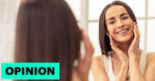 A brunette woman who has survived cancer, smiling in a mirror reflection 