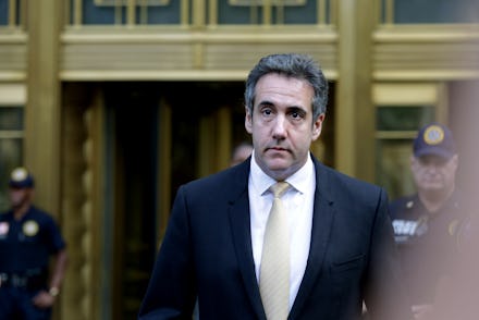 Michael Cohen in a black suit, a white shirt, and a beige satin tie walking