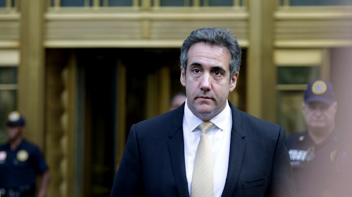 Michael Cohen in a black suit, a white shirt, and a beige satin tie walking
