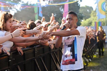 Wiley performing with a microphone and letting his fans touch his hand