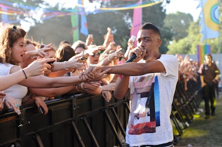 Wiley performing with a microphone and letting his fans touch his hand