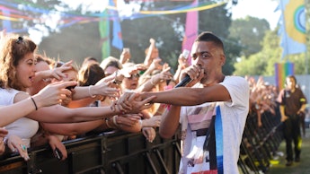 Wiley performing with a microphone and letting his fans touch his hand