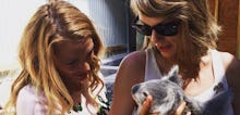 Taylor Swift and Blake Lively standing next to each other on a warm summer day holding a koala