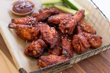 Dark chicken wings served in a box with barbecue sauce