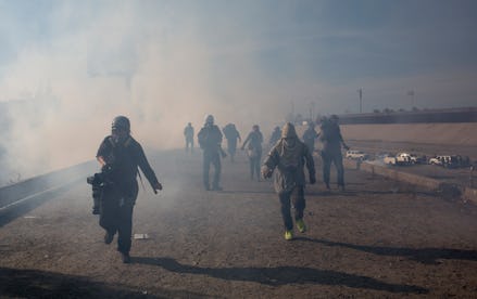 A group of migrants running after the use of tear gas at the Mexico border