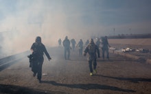 A group of migrants running after the use of tear gas at the Mexico border