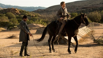 A scene from Westworld where one man is on a horse and another is standing behind him