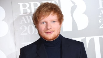 Ed Sheeran posing for a photo in a black sweater and blazer combination