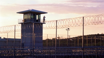 The outside view of a tower and wire fence of a US Criminal Justice system's building