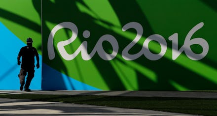 A man standing next to a green-blue-white wall with the text 'Rio 2016' for the Rio Olympics 2916