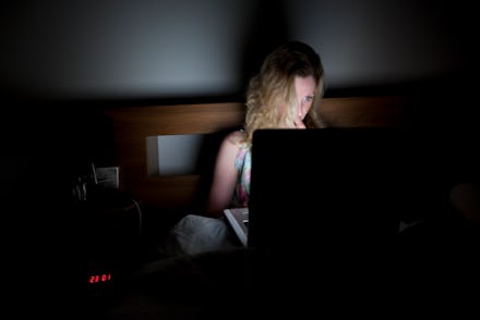 Woman searching for porn on her laptop in bed.