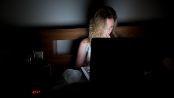 Woman searching for porn on her laptop in bed.