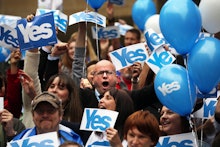 A group of people with yes signs and balloons advocating for scotlands independence from britain