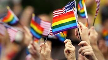Many hands waving small USA and LGBT flags