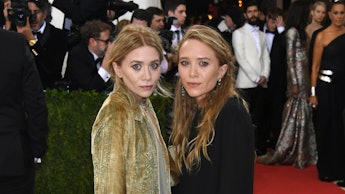 Mary-Kate and Ashley Olsen on a red carpet event wearing contrasting color outfits