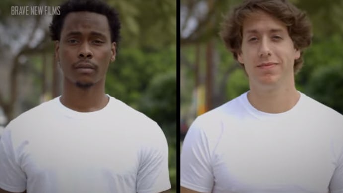 A white and black man standing next to each other in identical white shirts