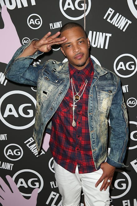 T.I. posing in a denim jacket, red plaid shirt, and white pants