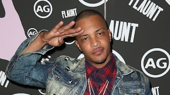 T.I. posing in a denim jacket, red plaid shirt, and white pants
