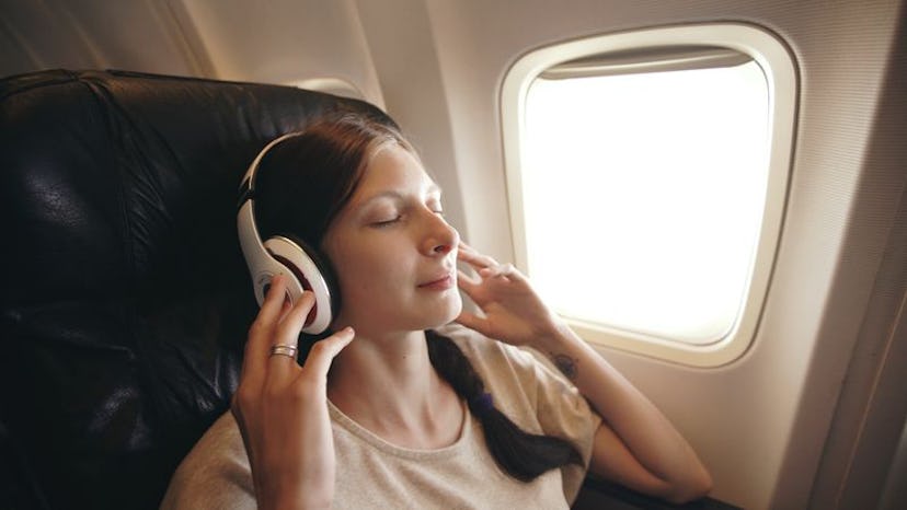 A woman sitting in a plane with large white earphones