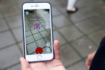 A man in new york holding his phone in front of him playing pokemon go