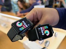 A man holding two Apple Watches with Apps on them running