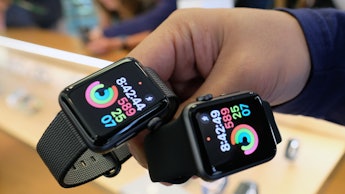 A man holding two Apple Watches with Apps on them running