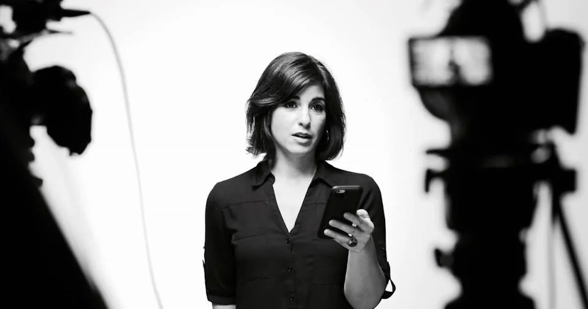 Natasha Del Toro holding a phone between two video cameras