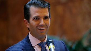 Donald Trump Jr. smiling while standing in front of a microphone at a political rally