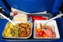 Airplaine food pack, containing rice, meat with sauce, beans, carrots, cherry tomato, and some bread...