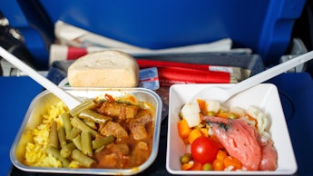 Airplaine food pack, containing rice, meat with sauce, beans, carrots, cherry tomato, and some bread...