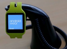 Green smartwatch with "android wear" text on its screen