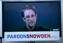 Edward Snowden on a TV screen with a text reading 'PardonSnowden.org' below his face