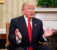 Donald Trump sitting on a chair while explaining something to a person across from him