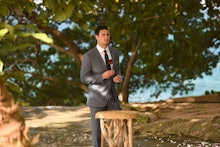 Ben Higgins from The Bachelor holding a rose in a suit and tie 