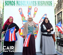 Three Muslim ladies posing for a photo with small Cuba flags