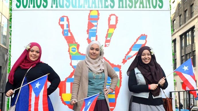 Three Muslim ladies posing for a photo with small Cuba flags