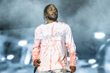 Kenrick Lamar in a white-orange shirt and pants, performing on stage