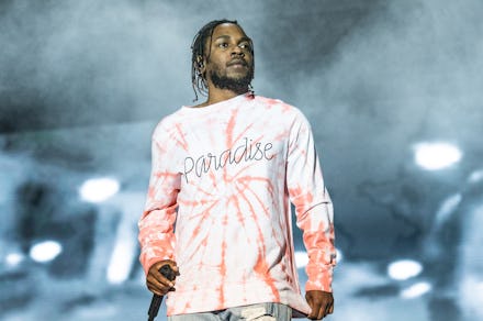 Kenrick Lamar in a white-orange shirt and pants, performing on stage