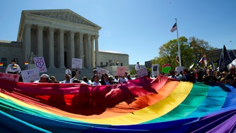 A group of LGBTQ rights protester holding a large flag in front of the U.S. Capitol