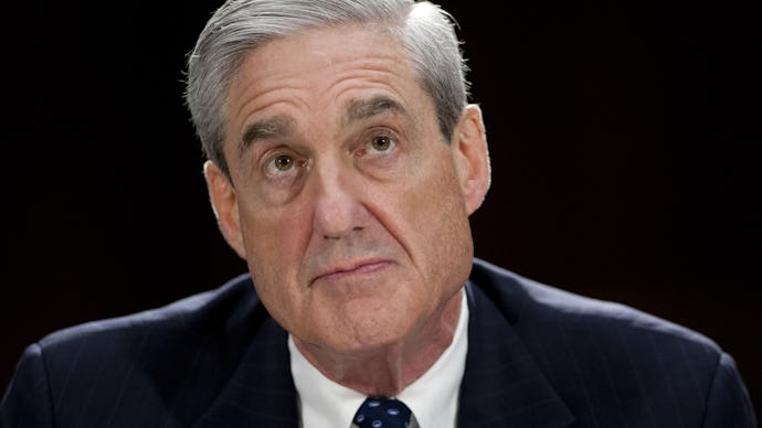 Robert Mueller in a suit, staring above him while being backlit and sitting in front of black backgr...