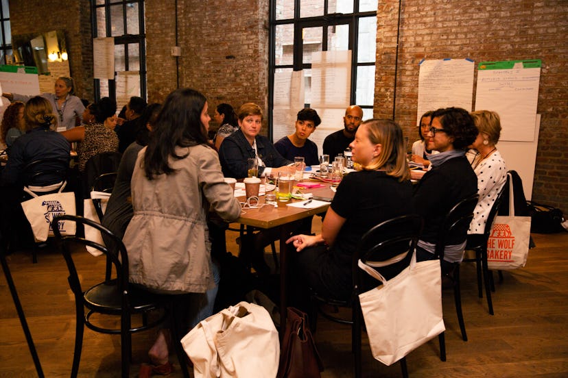 Group of women that are working in restaurants sitting together at a restaurant table and eating