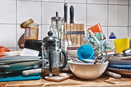 A pile of various kitchen utensils and dishes on a cupboard surface